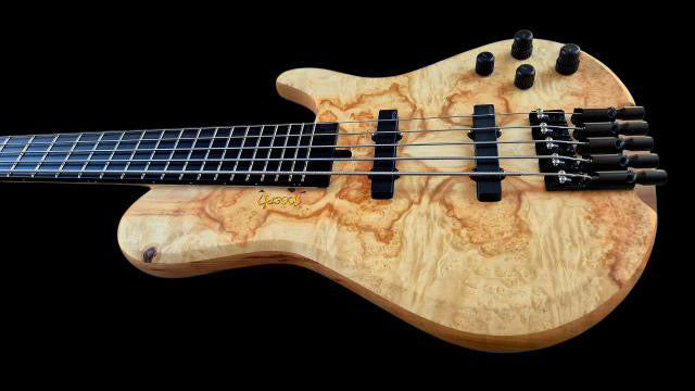 Wooden electric bass guitar with a black background